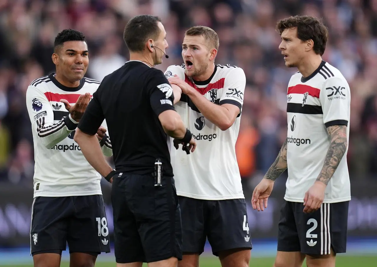 Manchester United players protest to referee David Coote after the award of a penalty against West Ham