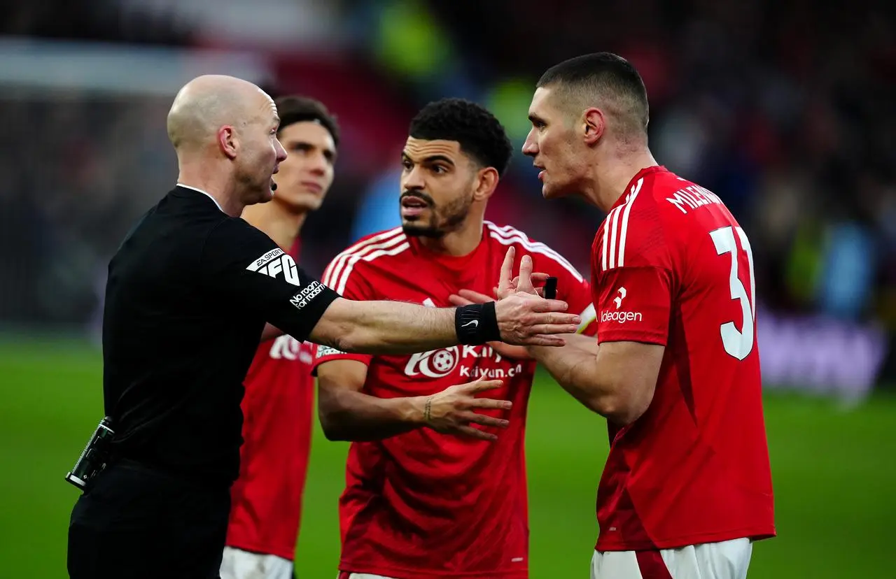 Referee Anthony Taylor speaks to Nottingham Forest’s Morgan Gibbs-White and Nikola Milenkovic after ruling out the latters goal for an offside after checking the pitchside VAR monitor during the Premier League match at the City Ground, Nottingham.
