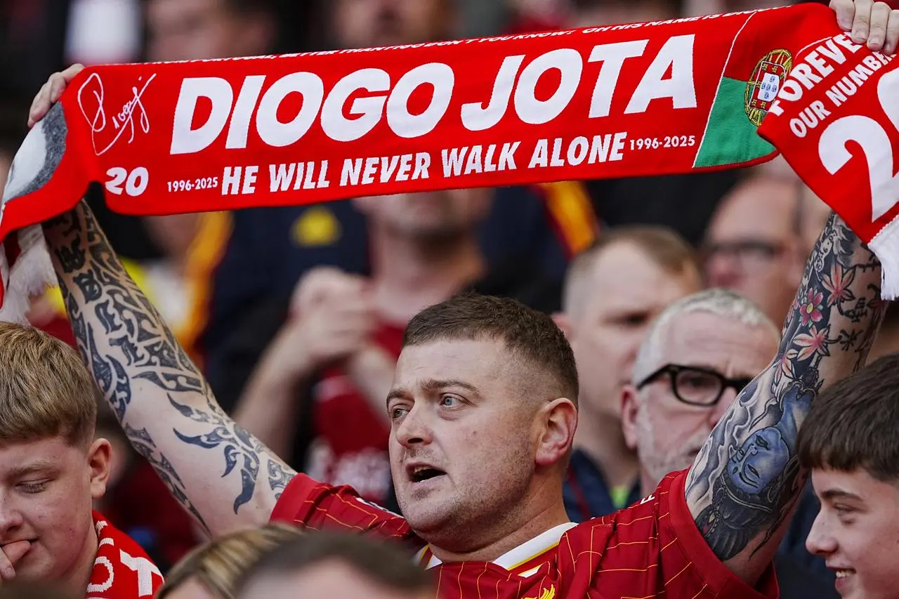 A Liverpool fan holding a Diogo Jota scarf
