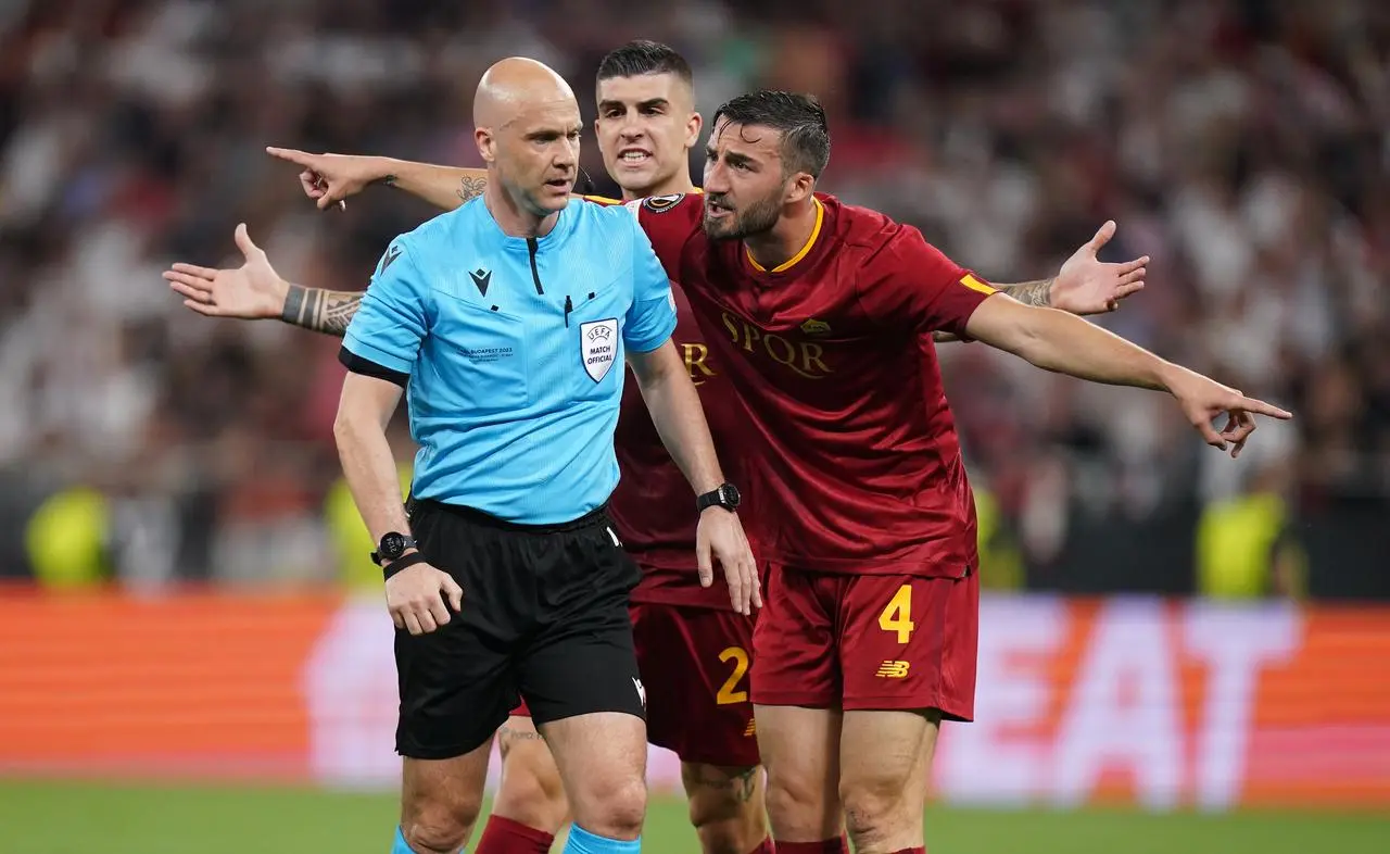 Referee Anthony Taylor is surrounded by Roma players during the 2023 Europa League final in Budapest