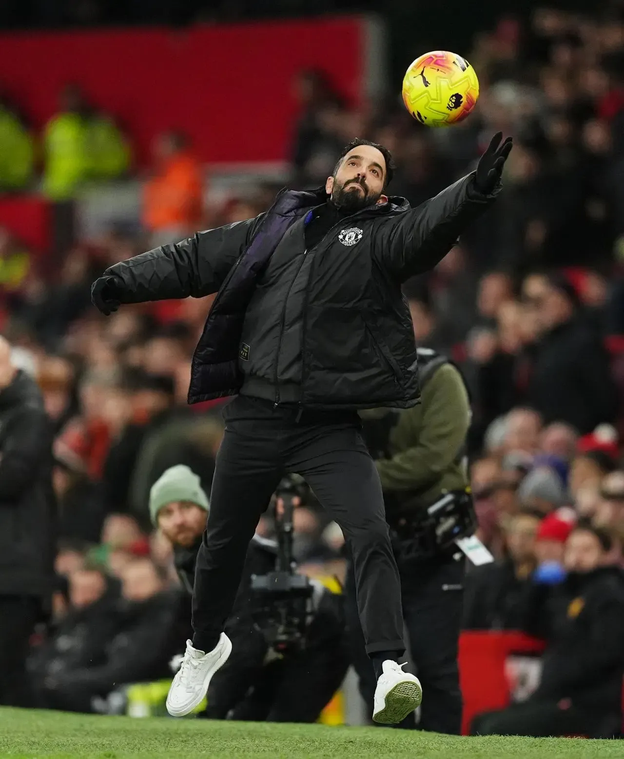 Manchester United manager Ruben Amorim stretches out his left arm to collect a ball flying high off the pitch