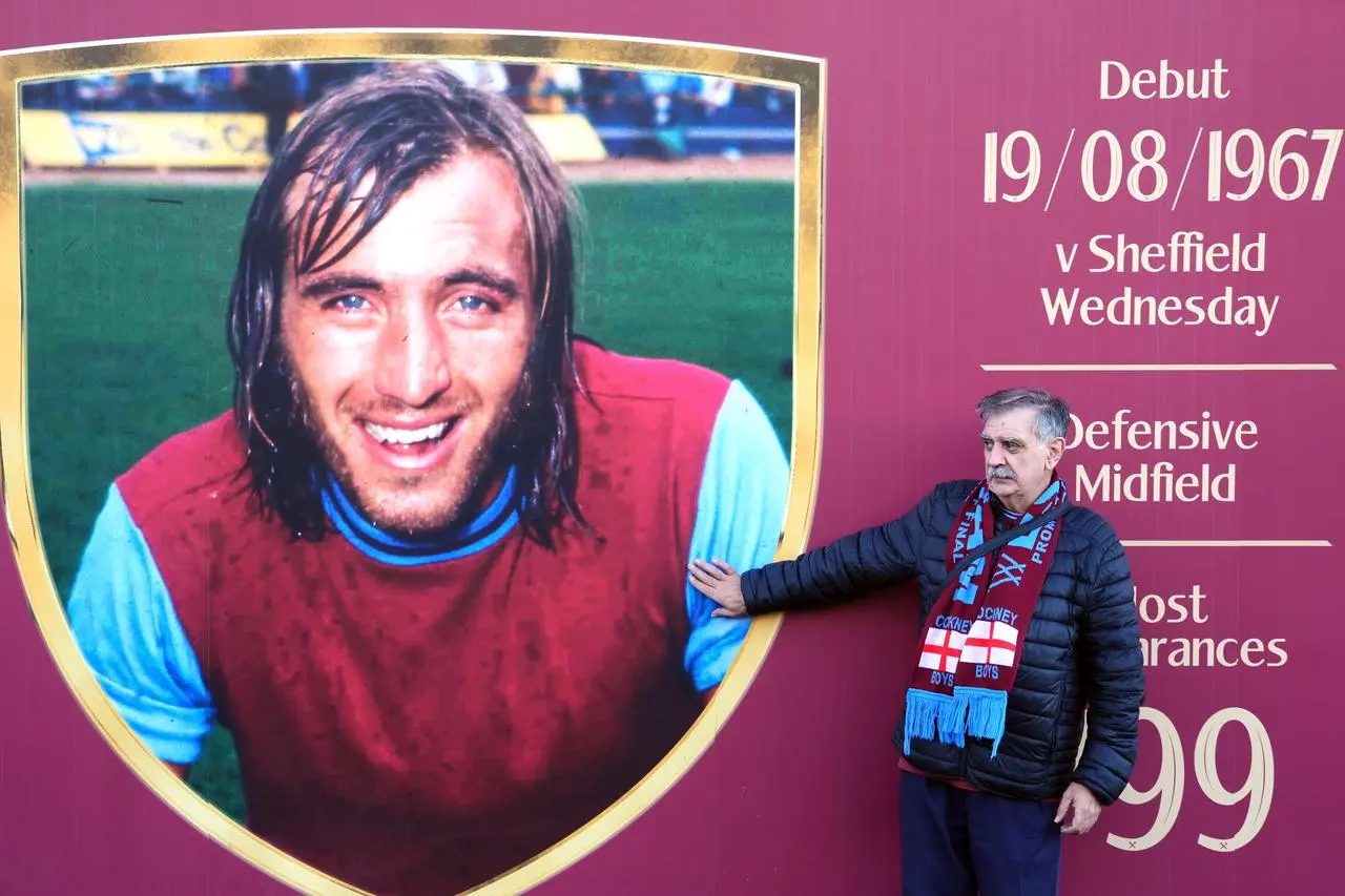 Fans stand by a mural of former West Ham United player and manager Billy Bonds outside the London Stadium