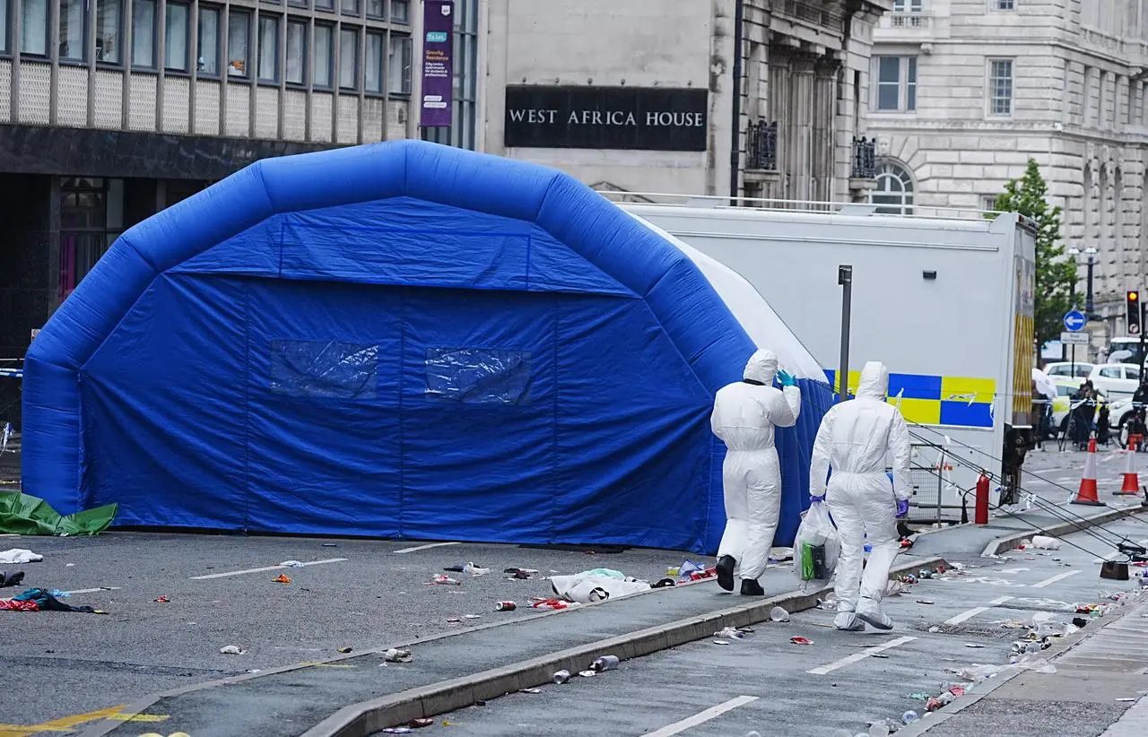 Forensic officers walk past an inflatable field tent at the scene in Water Street in Liverpool
