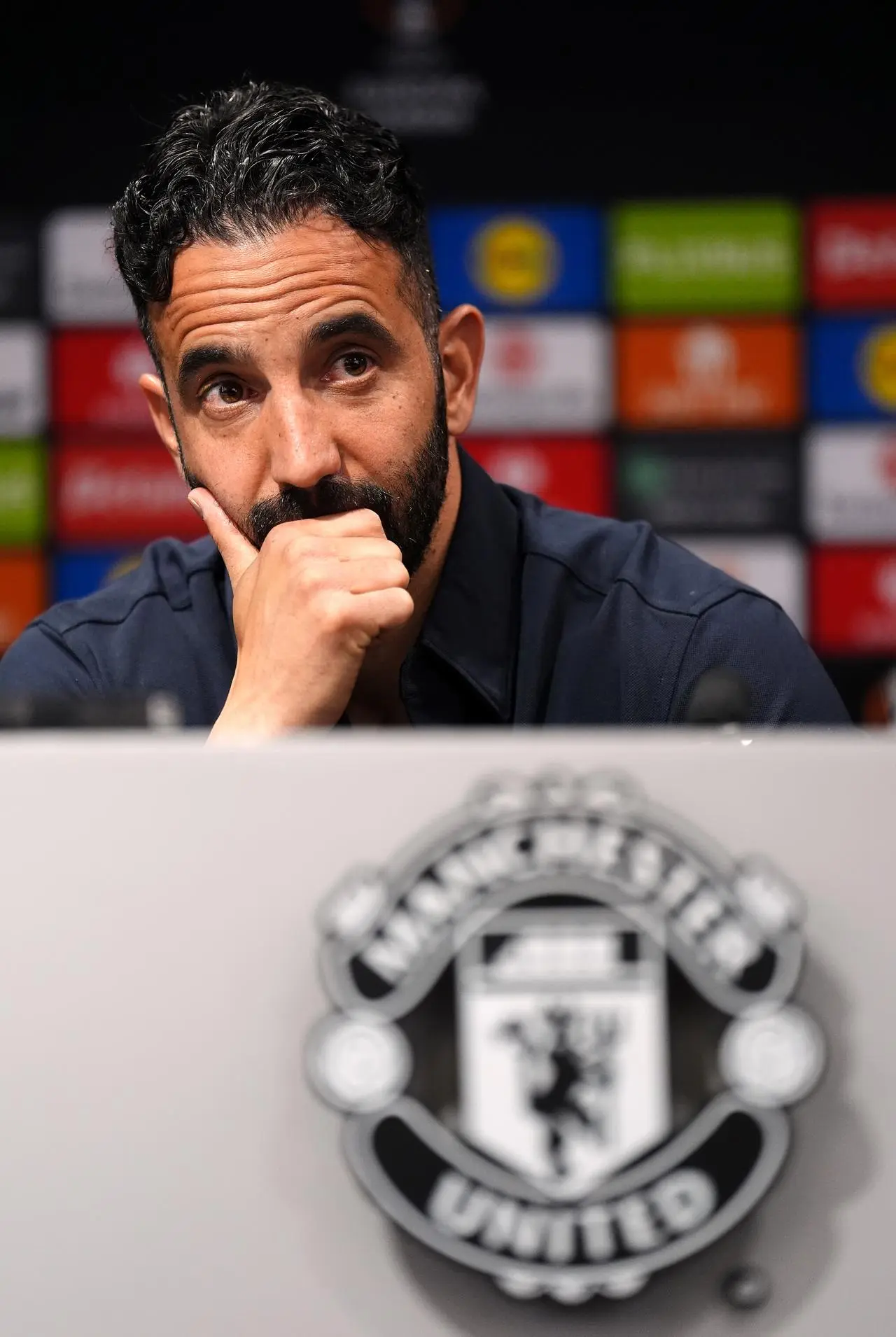 Ruben Amorim sits behind a Manchester United logo in a press conference