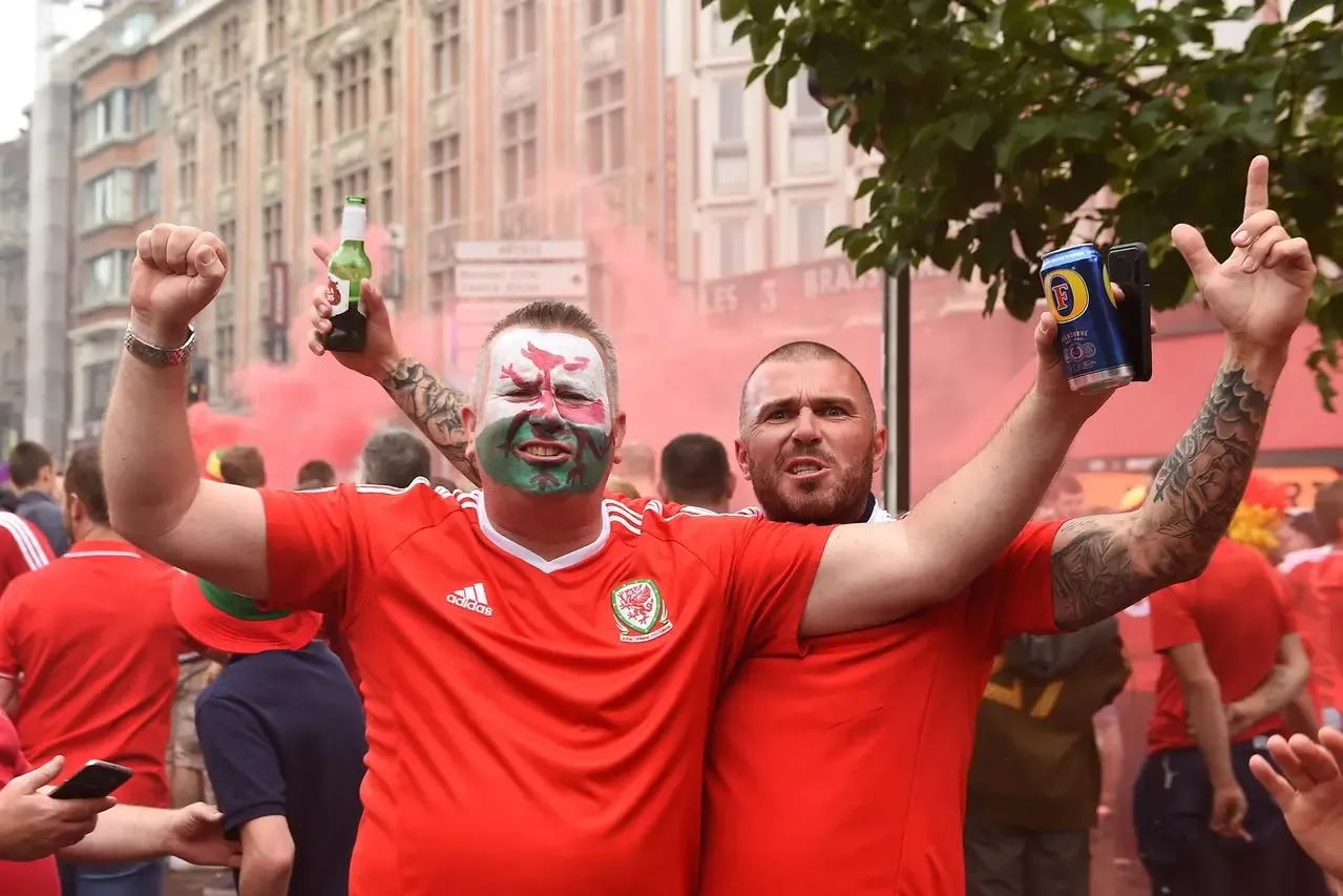 Two Wales fans celebrating with beers in hand