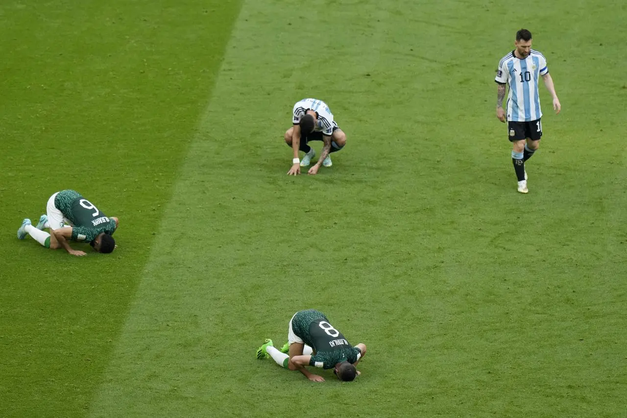 Argentina’s Lionel Messi leaves the field as three Saudi Arabia players kneel on the turf