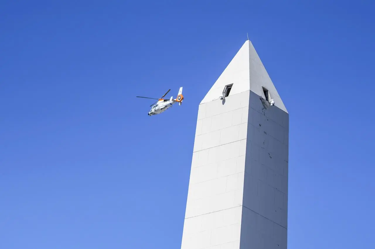 A helicopter flies over the Obelisk