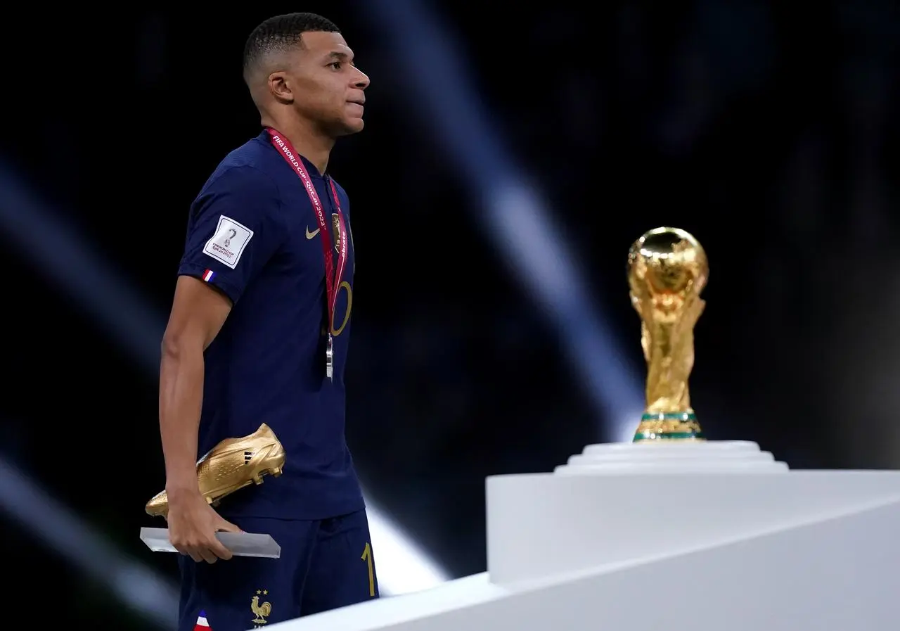 Kylian Mbappe walks past the World Cup trophy with his runner-up medal and Golden Boot trophy