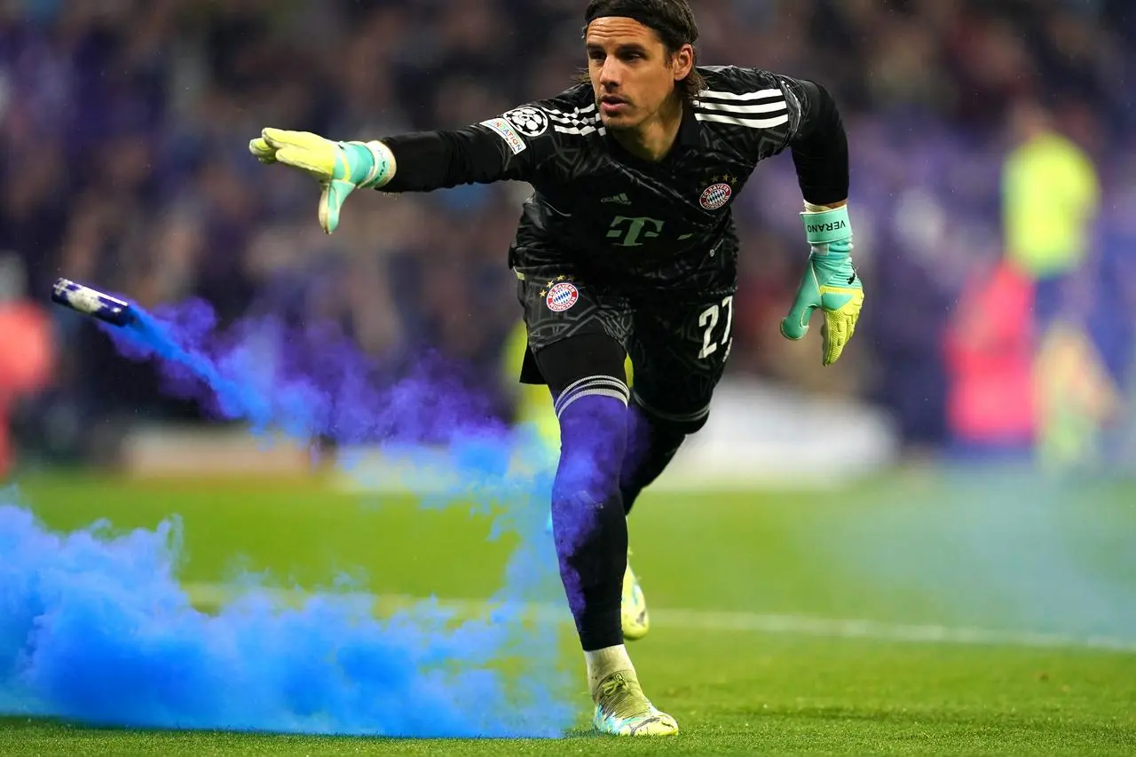 Bayern Munich goalkeeper Yann Sommer removes a blue flare from the field