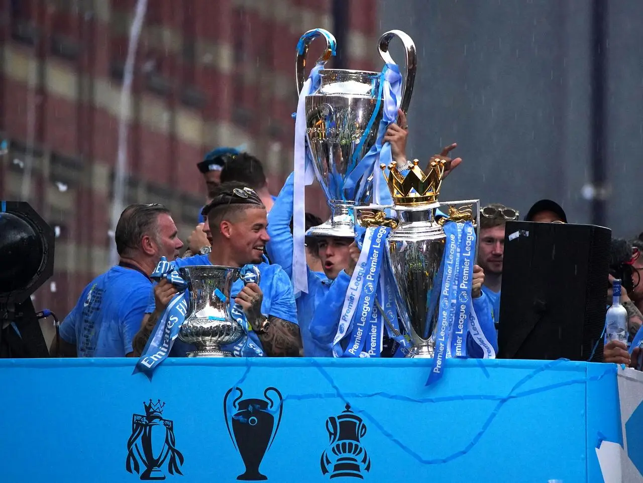 Manchester City’s Kalvin Phillips with the FA Cup trophy, Phil Foden with the Champions League trophy, and Bernardo Silva with the Premier League trophy