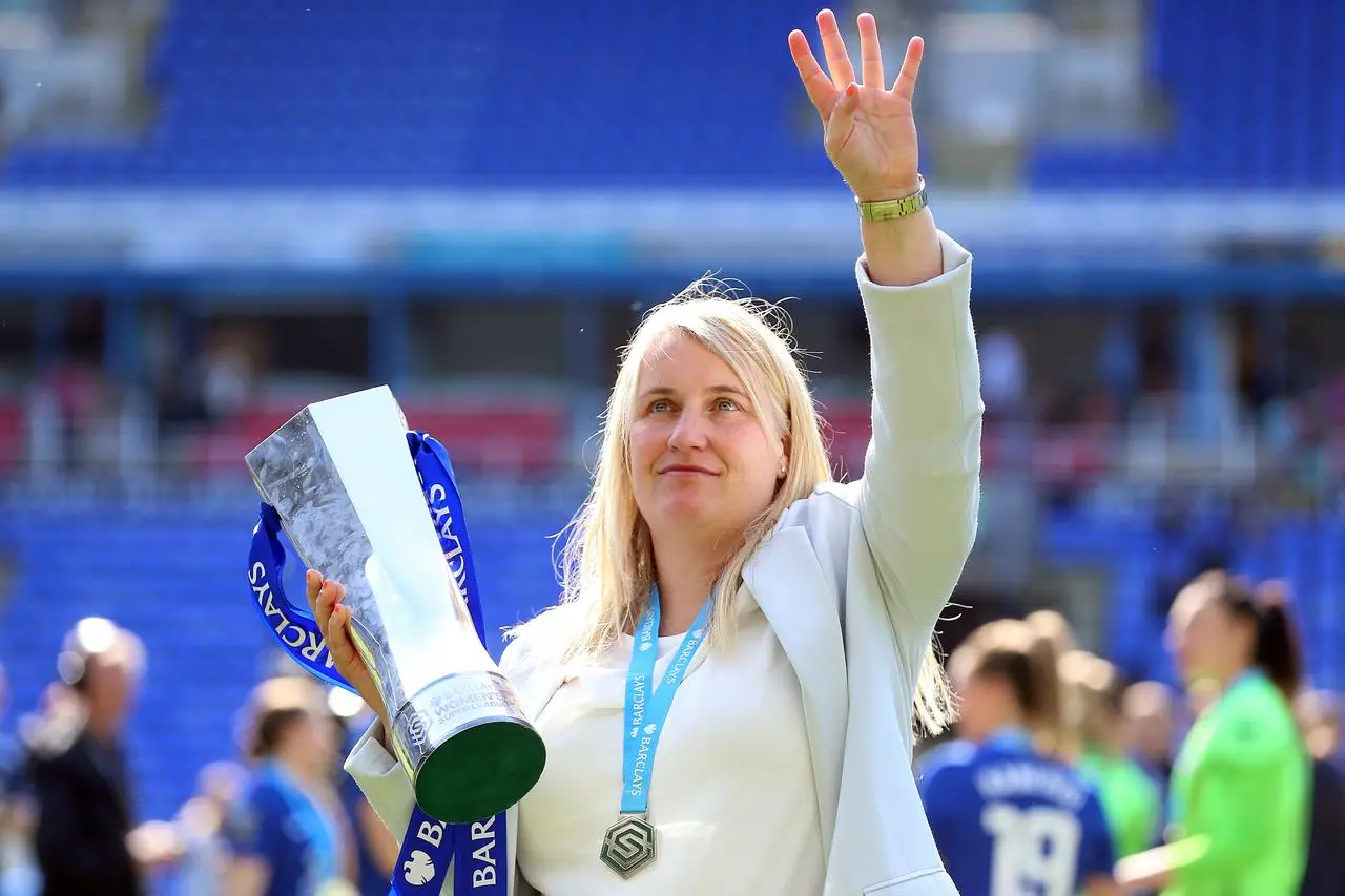 Emma Hayes raises four fingers while holding the WSL trophy