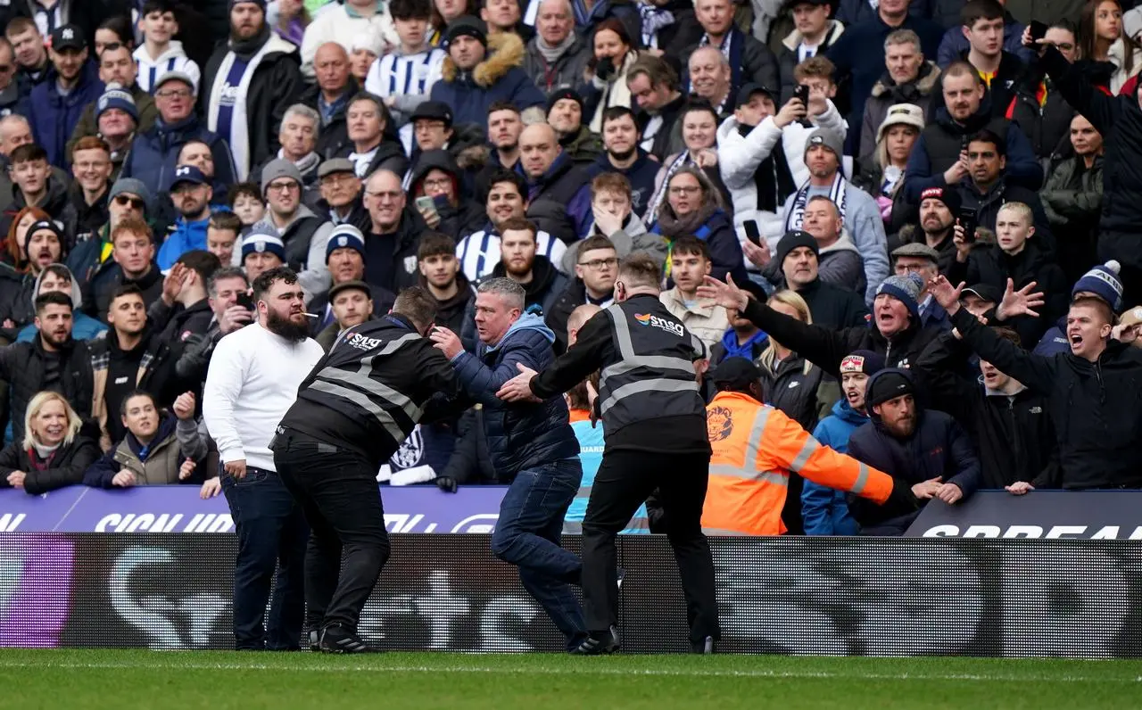 Stewards attempt to apprehend fans as they enter the pitch during the FA Cup fourth round match at The Hawthorns