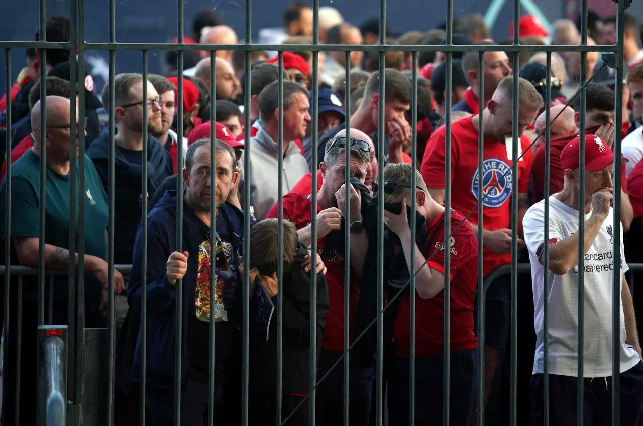 Liverpool fans cover their mouths and noses as they queue to gain entry to the 2022 Champions League final