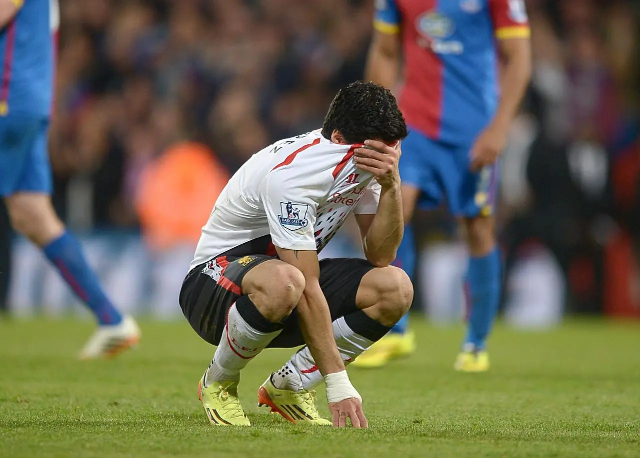 Liverpool’s Luis Suarez covers his face with his shirt