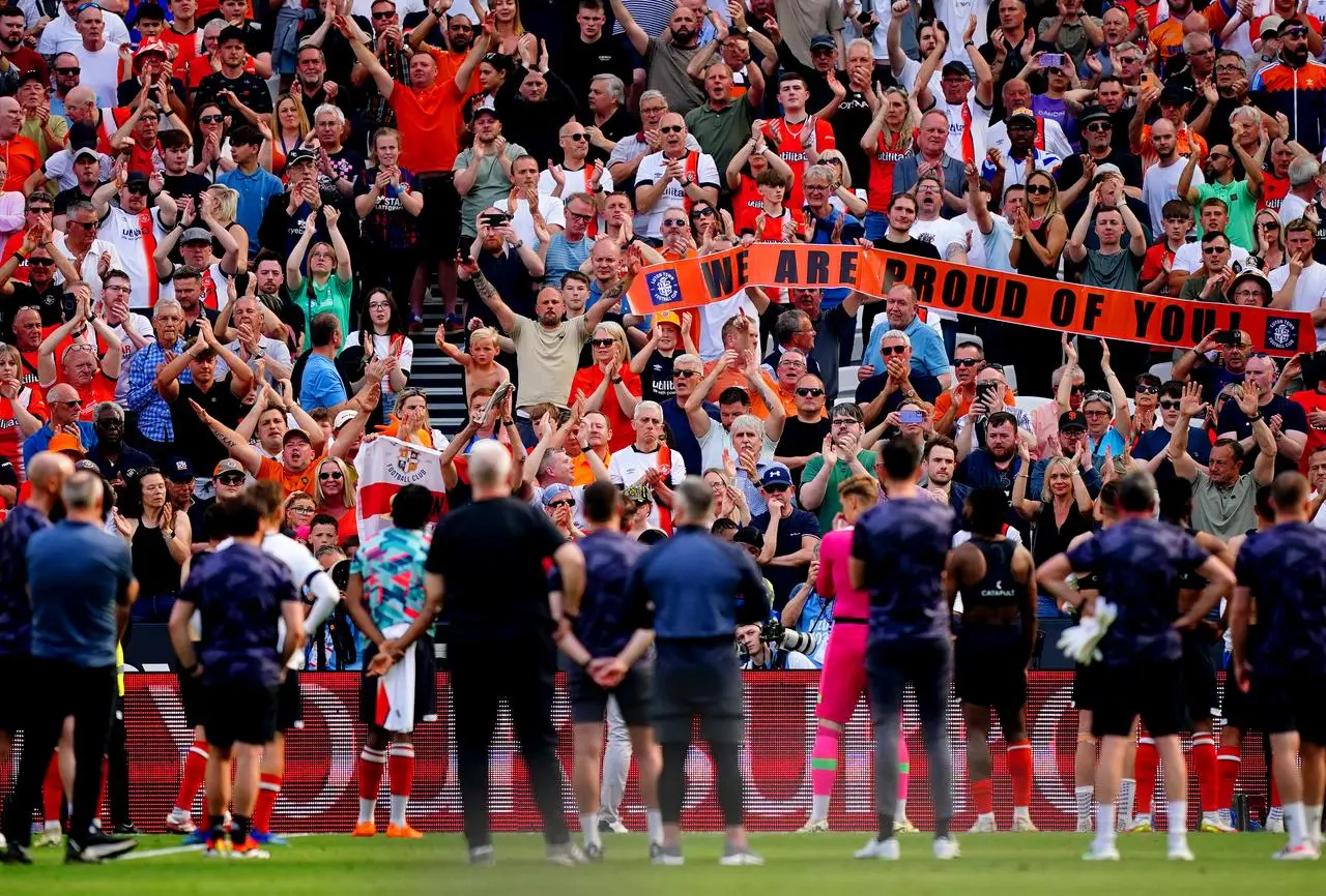 Luton fans applaud their players and hold up a banner reading 'We are proud of you' after defeat to West Ham