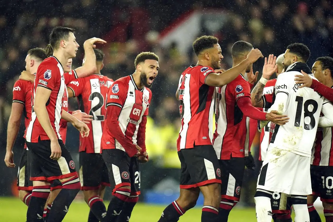 Sheffield United players embrace goalkeeper Wes Foderingham, second right, after December's win over Brentford