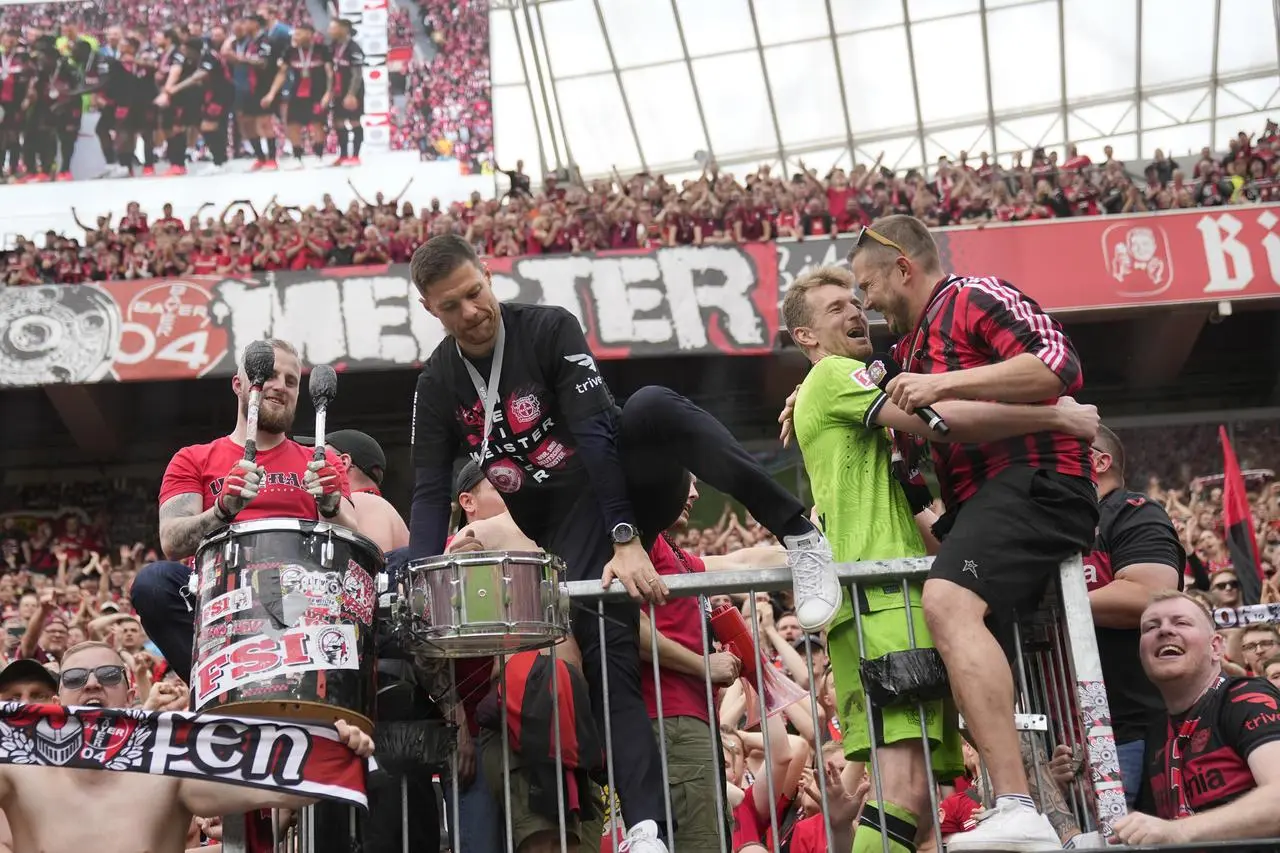Leverkusen’s head coach Xabi Alonso (centre) and goalkeeper Lukas Hradecky celebrate with fans