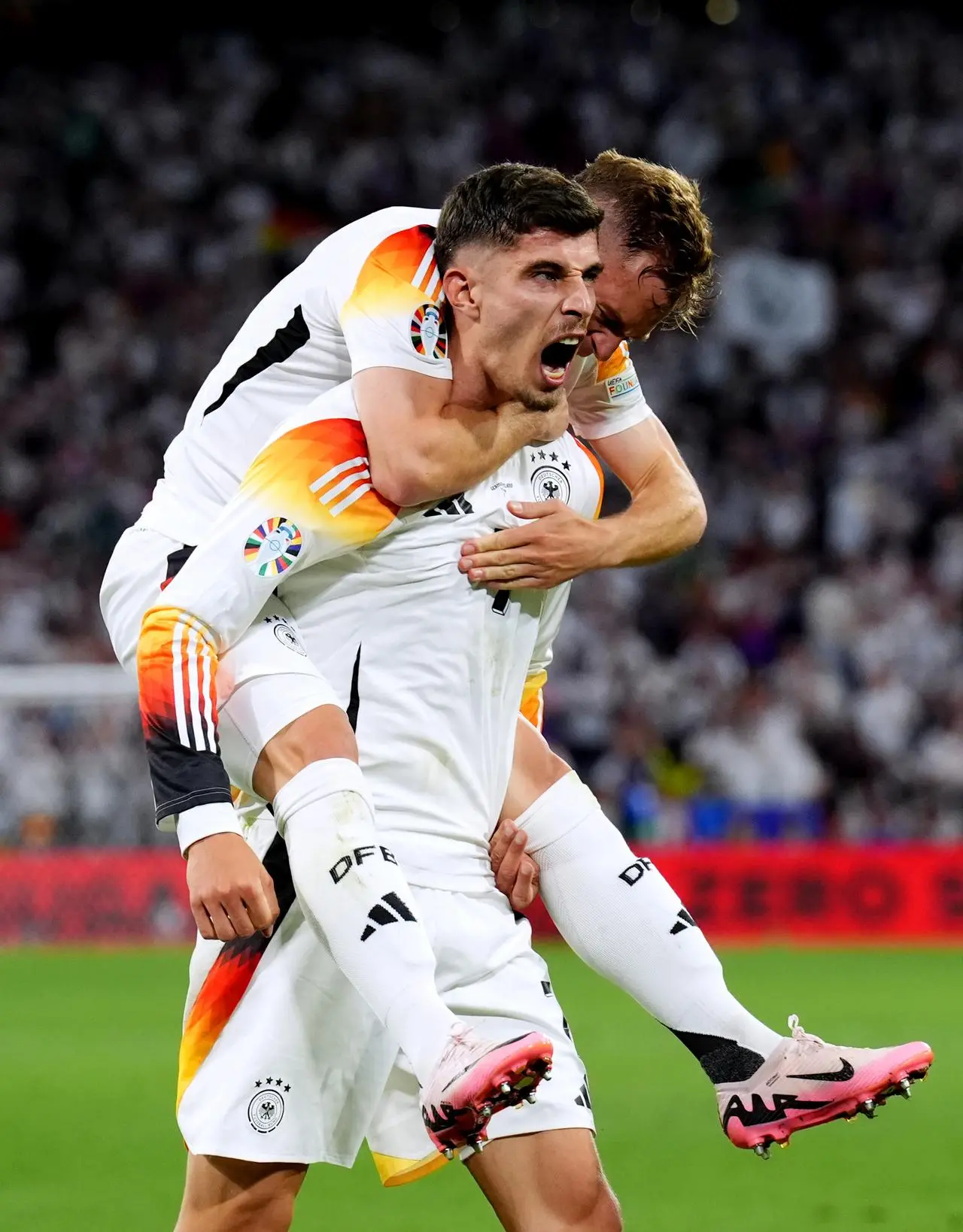 Kai Havertz, bottom, celebrates his goal against Scotland as Germany team-mate Joshua Kimmich jumps on his back