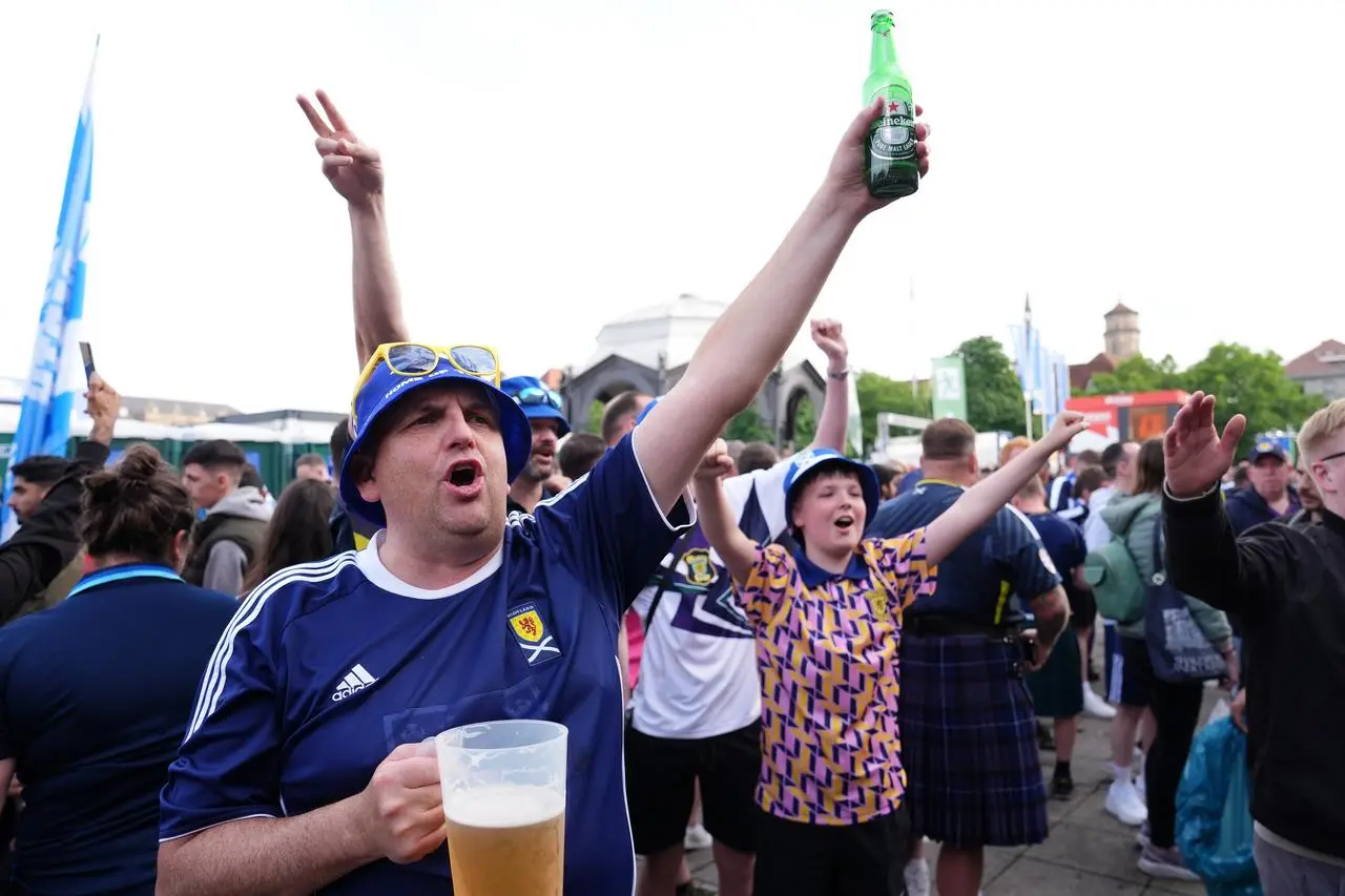 Scotland fans in Stuttgart hold up beer bottles