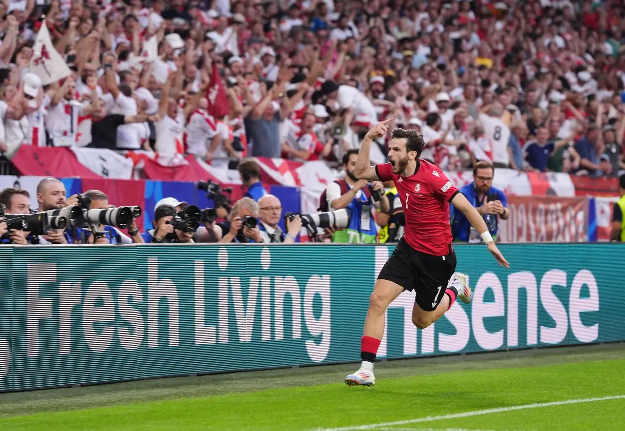 Khvicha Kvaratskhelia, with his arms out, runs to the corner flag to celebrate scoring against Portugal