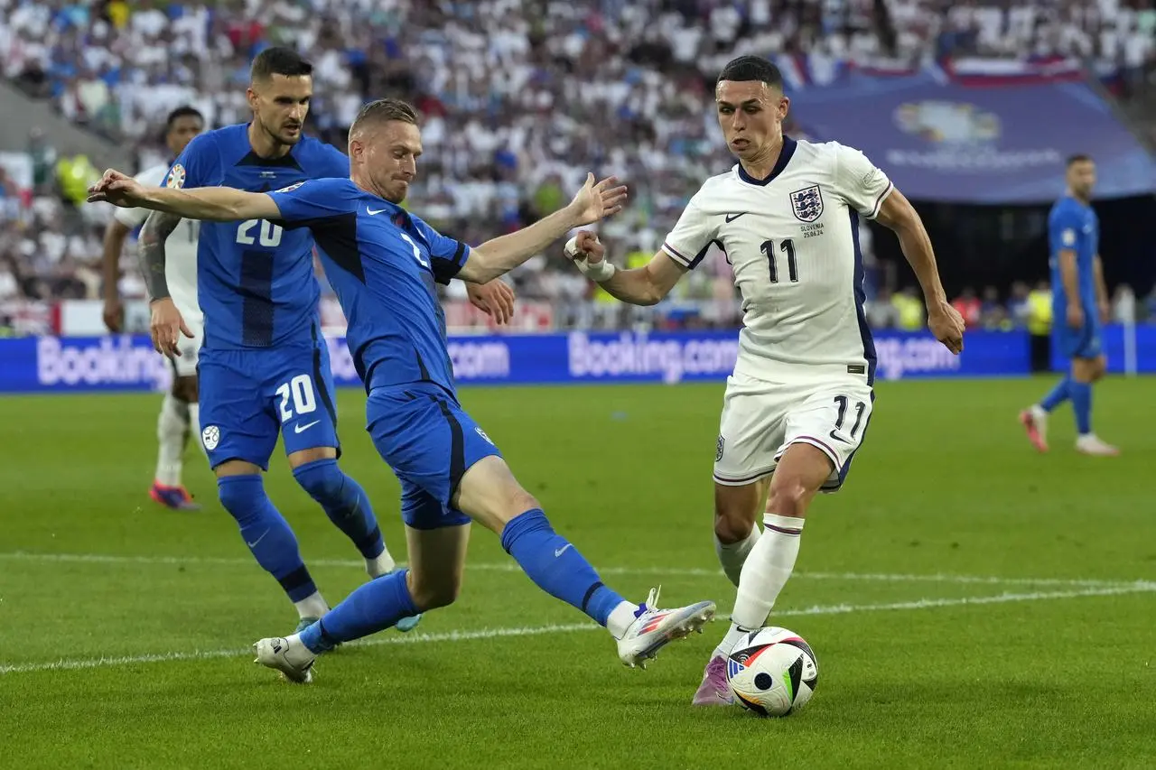 Phil Foden, right, moves the ball as Slovenia’s Zan Karnicnik, center, reaches in and Petar Stojanovic watches during a Group C match between the England and Slovenia