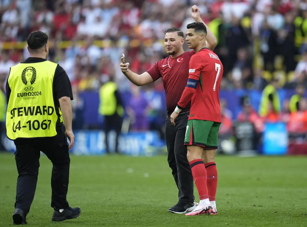 A pitch invader attempts to get a photo with Portugal’s Cristiano Ronaldo before security intervene