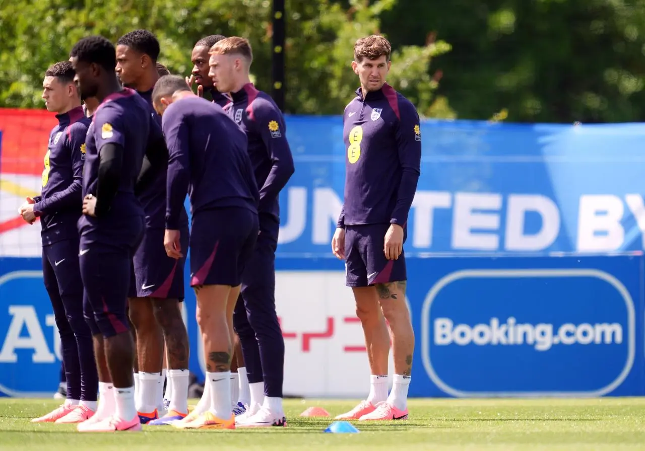 John Stones, right, stands slightly separate from a group of England players listening to instructions in training