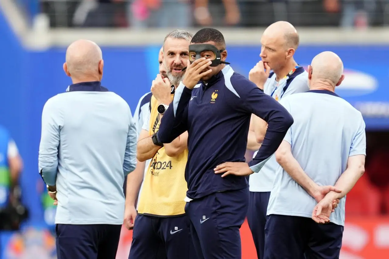 Kylian Mbappe, centre, with a protective mask on his face as he warms up before the UEFA Euro 2024 Group D match