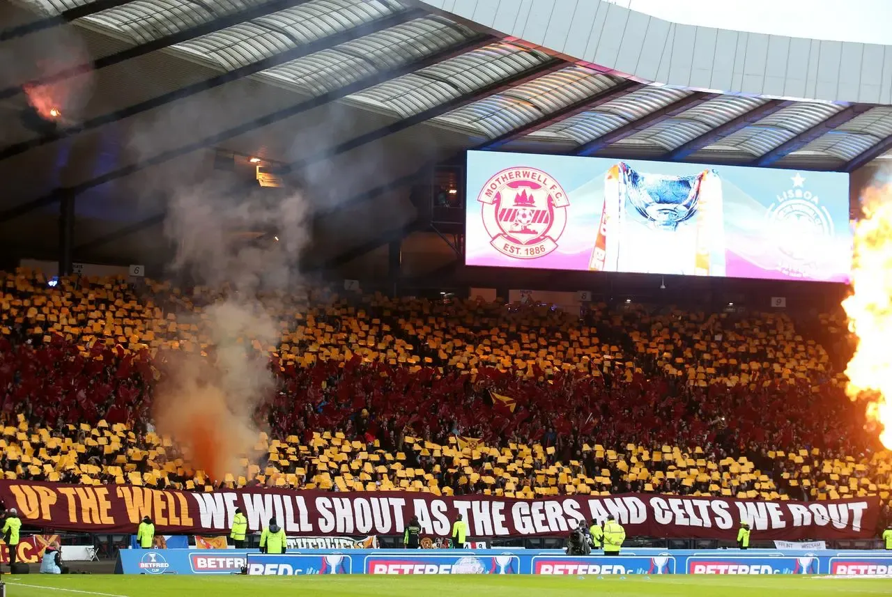 Motherwell fans at Hampden holding up claret and amber cards