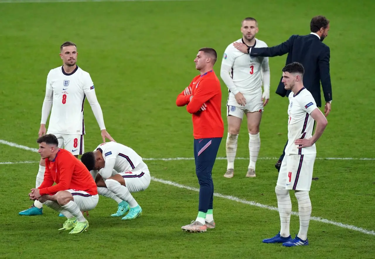 Gareth Southgate embraces Luke Shaw as his England team-mates show their dejection after losing the Euro 2020 final on penalties