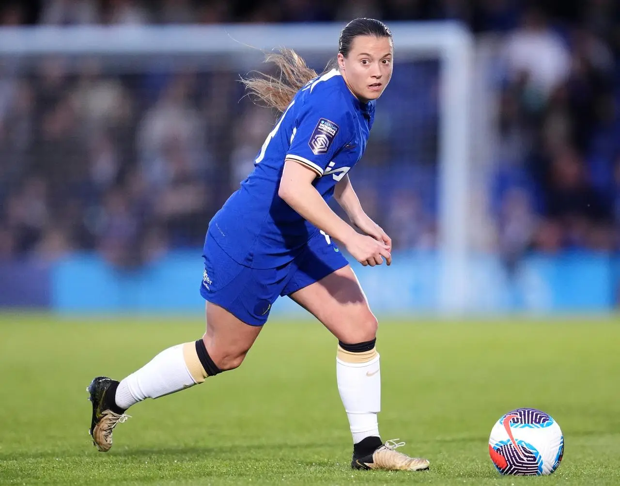 Fran Kirby, in a dark blue Chelsea shirt and shorts, runs after a ball