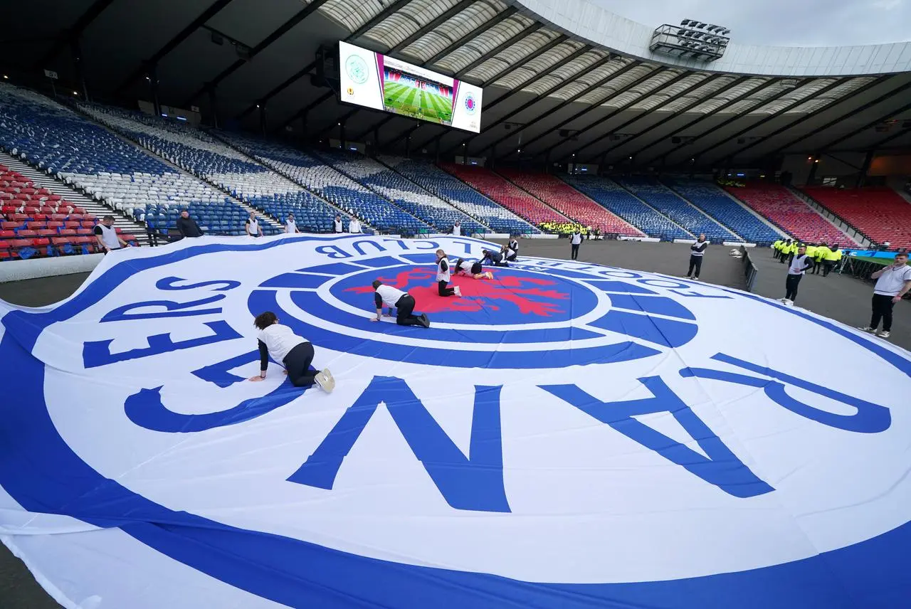 Stewards lay a Rangers banner on the Hampden pitch