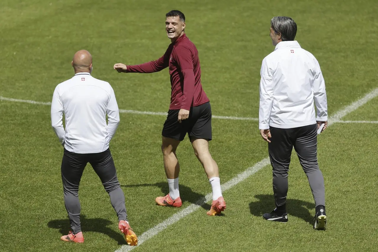 Switzerland’s head coach Murat Yakin, right, and assistant coach Giorgio Contini, left, talk to captain Granit Xhaka during a training session