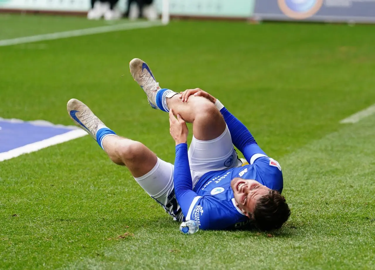 Ollie Tanner holds his leg in pain as he lies on the floor