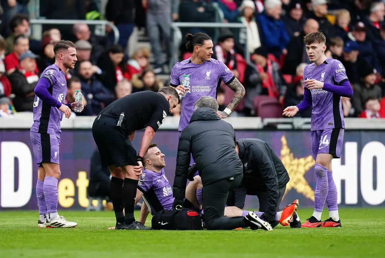 Liverpool’s Diogo Jota, centre, sits on the turf receiving treatment after picking up an injury against Brentford in February