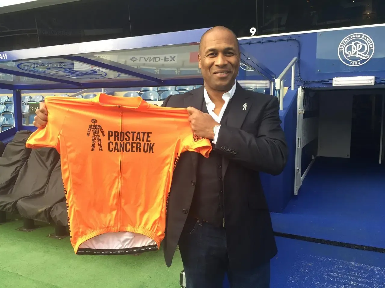 Les Ferdinand holding a Prostate Cancer UK charity shirt