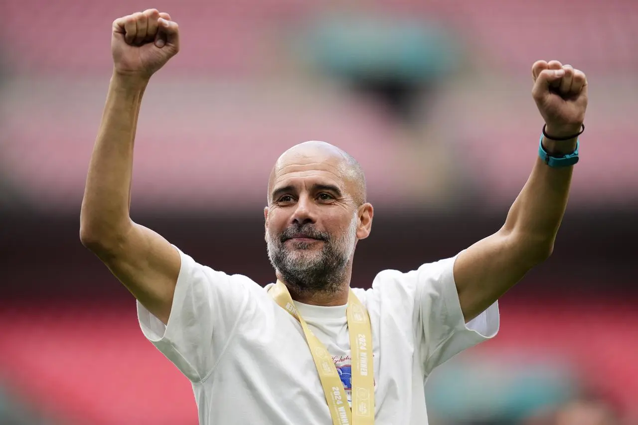 Pep Guardiola raises his arms aloft