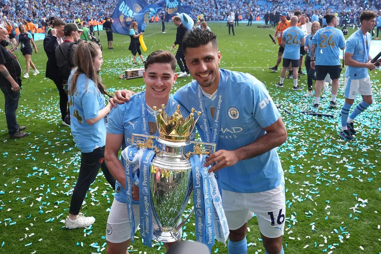 Julian Alvarez and Rodri hold the Premier League trophy