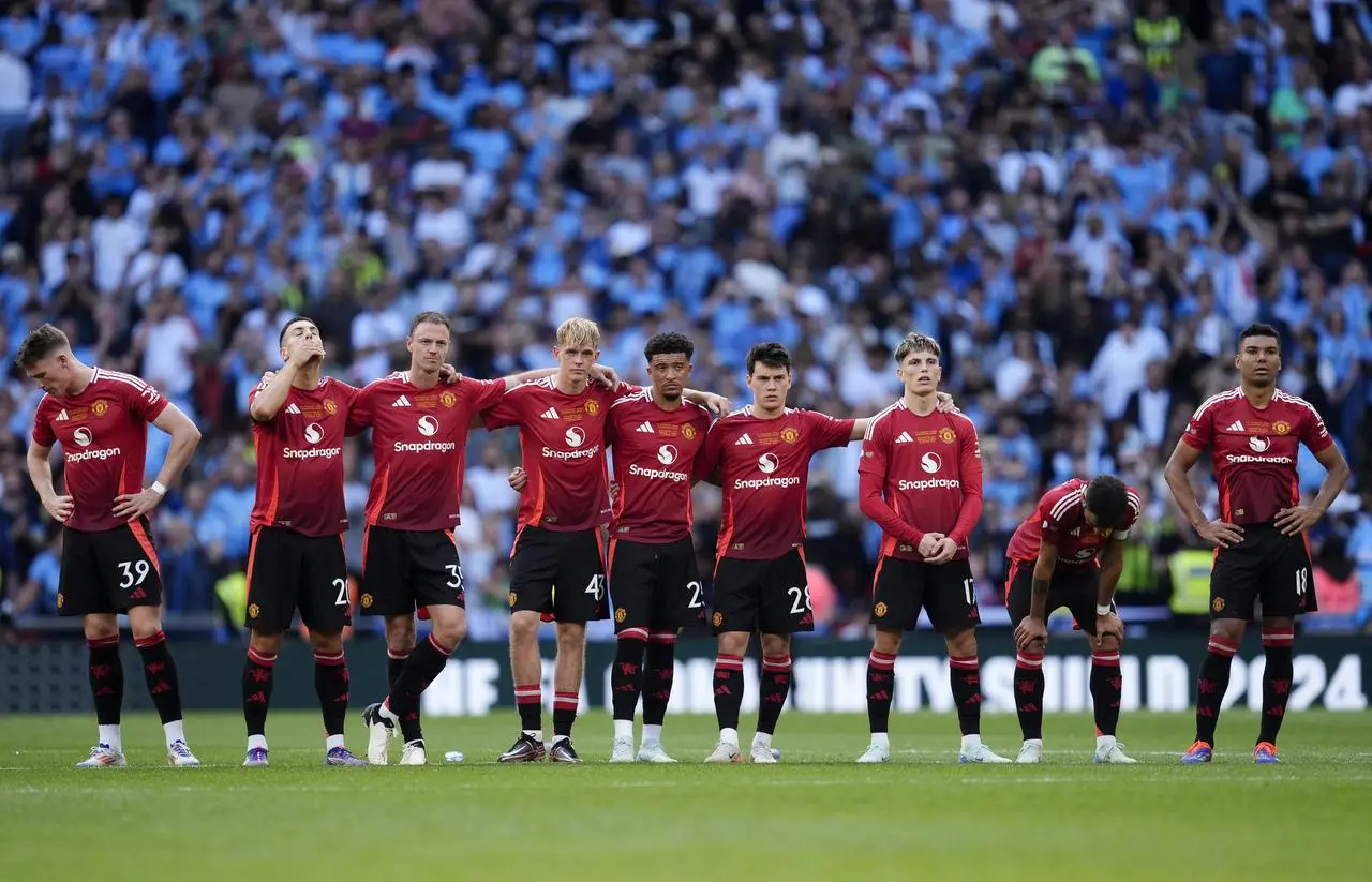 Manchester United players stand dejected on the halfway line during the penalty shootout