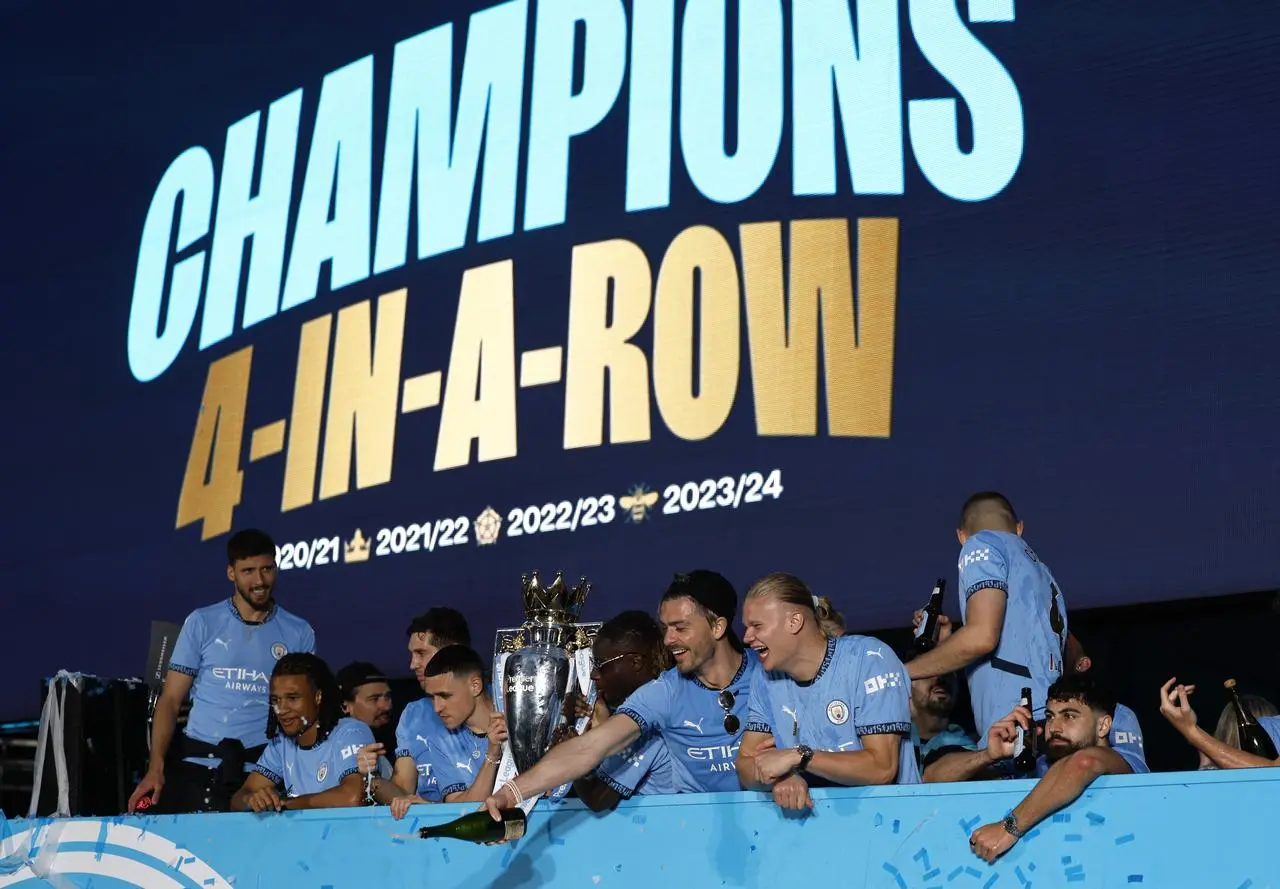 Manchester City players celebrate with the Premier League trophy at a parade to celebrate their title success