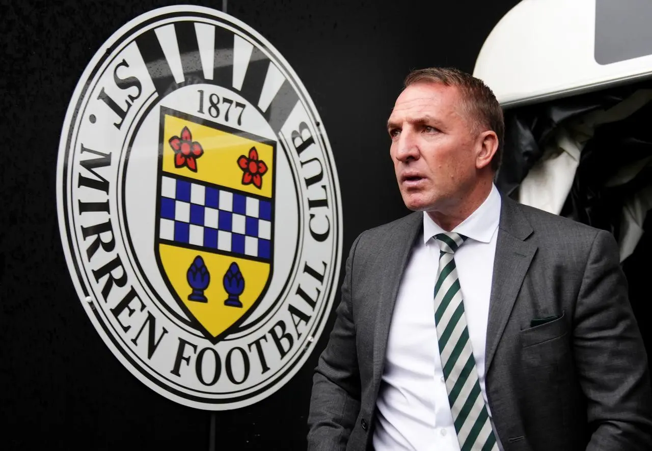 Celtic boss Brendan Rodgers, wearing a suit, walks past the St Mirren badge in the tunnel