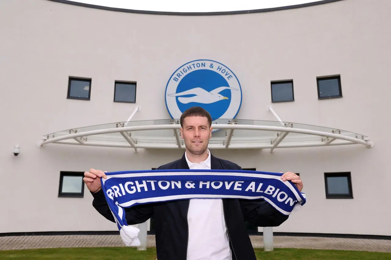 New Brighton head coach Fabian Hurzeler holds up a club scarf outside the training ground 