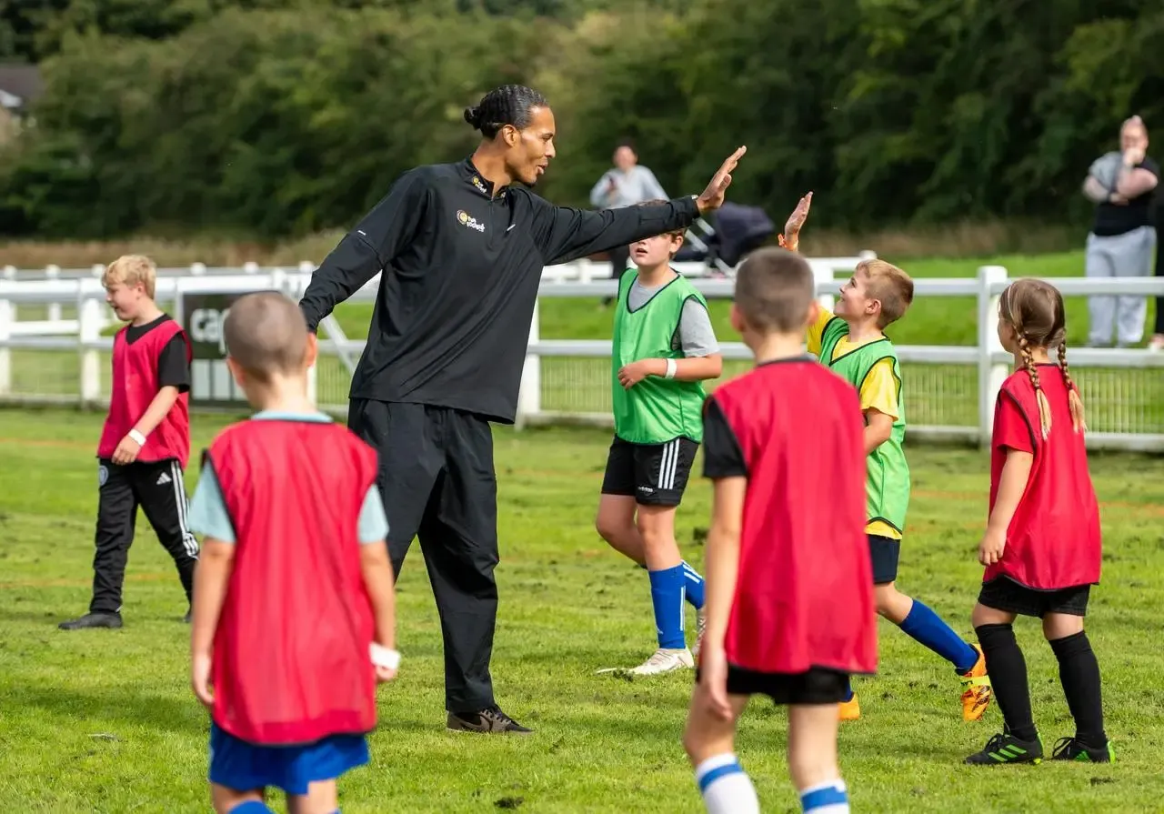 Liverpool captain Virgil van Dijk high fives a young boy during a training session