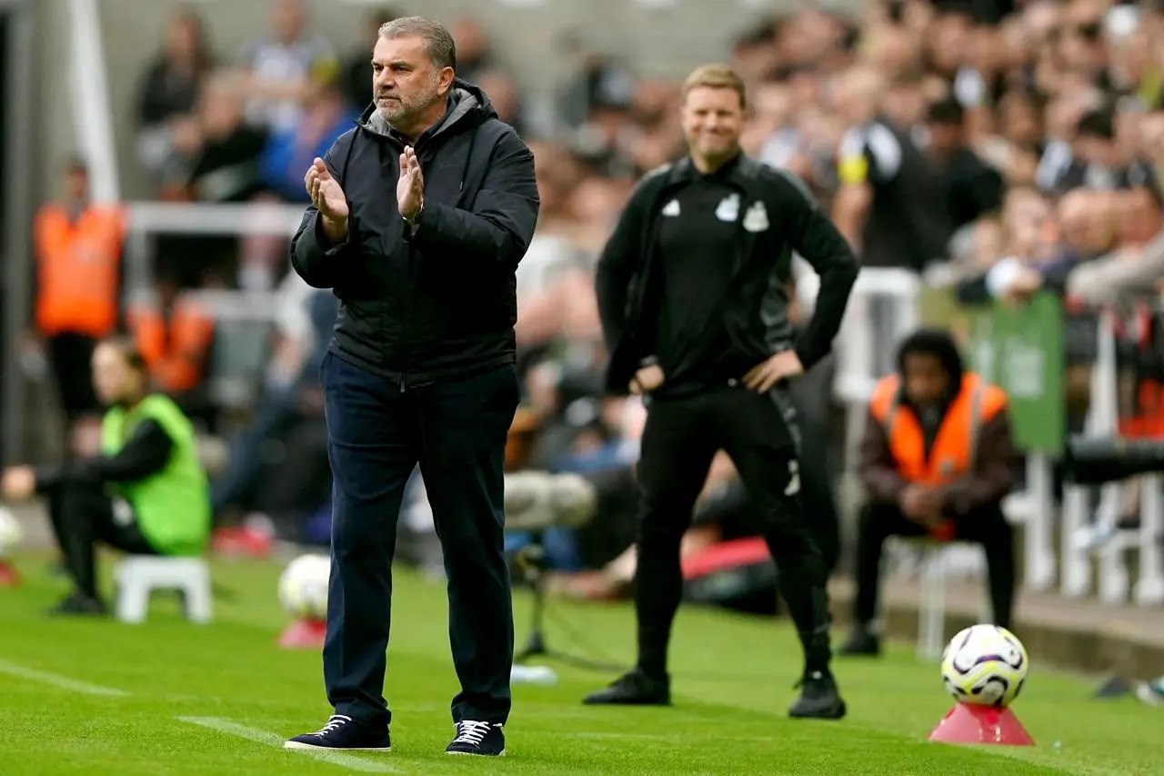 Ange Postecoglou claps to encourage his Tottenham side as Newcastle manager Eddie Howe looks on in the background