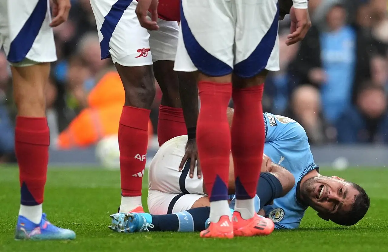 Manchester City midfielder Rodri lays on the floor injured as Arsenal players surround him