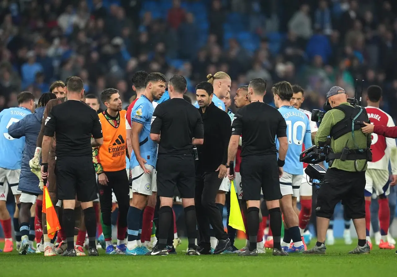 Arsenal manager Mikel Arteta, stood in a group of players and officials, speaks to the referee following the Premier League match at Manchester City