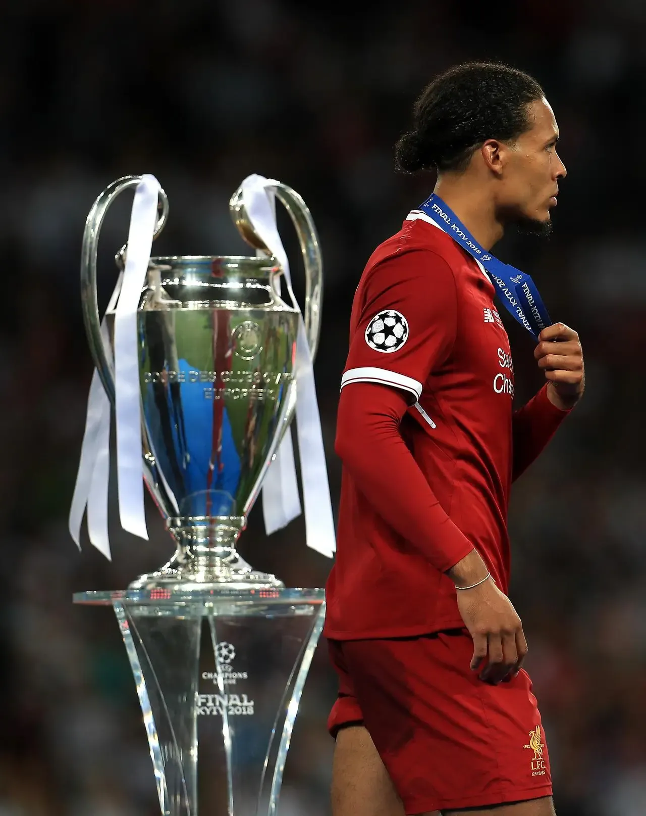 Liverpool defender Virgil van Dijk walks past the Champions League trophy