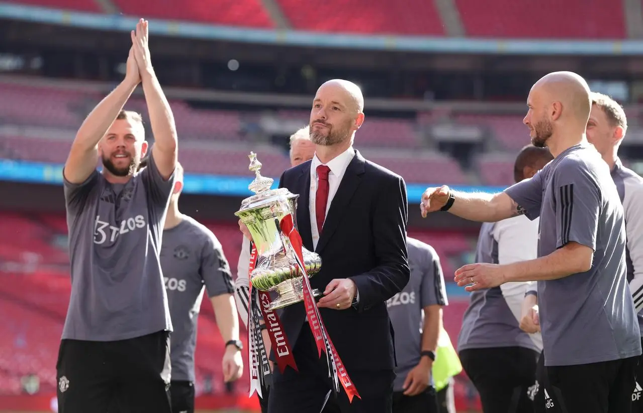 Manchester United manager Erik ten Hag, centre, surrounded by his coaching staff as he holds the FA Cup