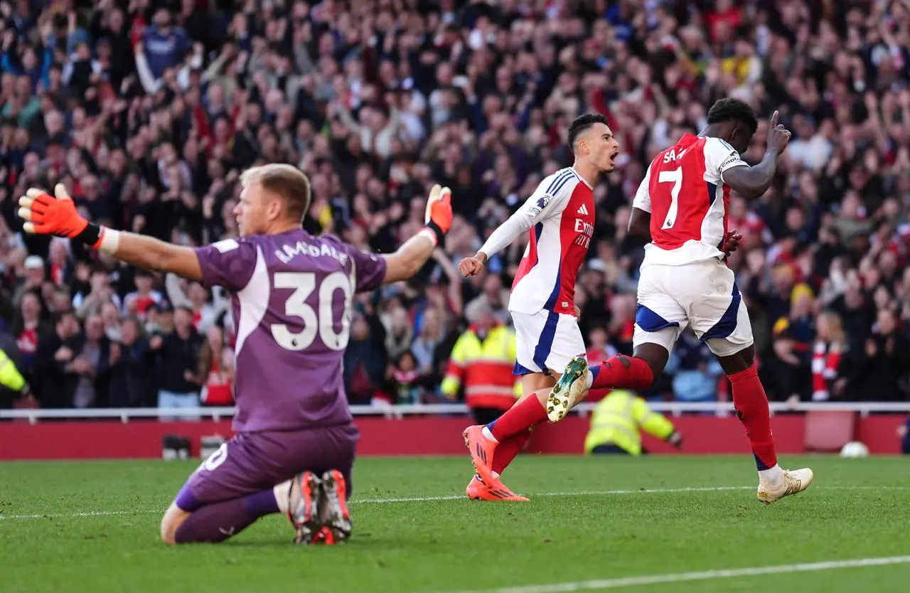 Arsenal’s Bukayo Saka runs away to celebrate as Aaron Ramsdale gestures with his arms