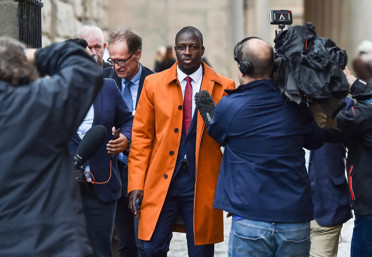 Benjamin Mendy in orange jacket surrounded by photographers